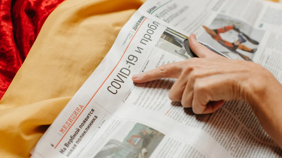 person reading and pointing at a newspaper article